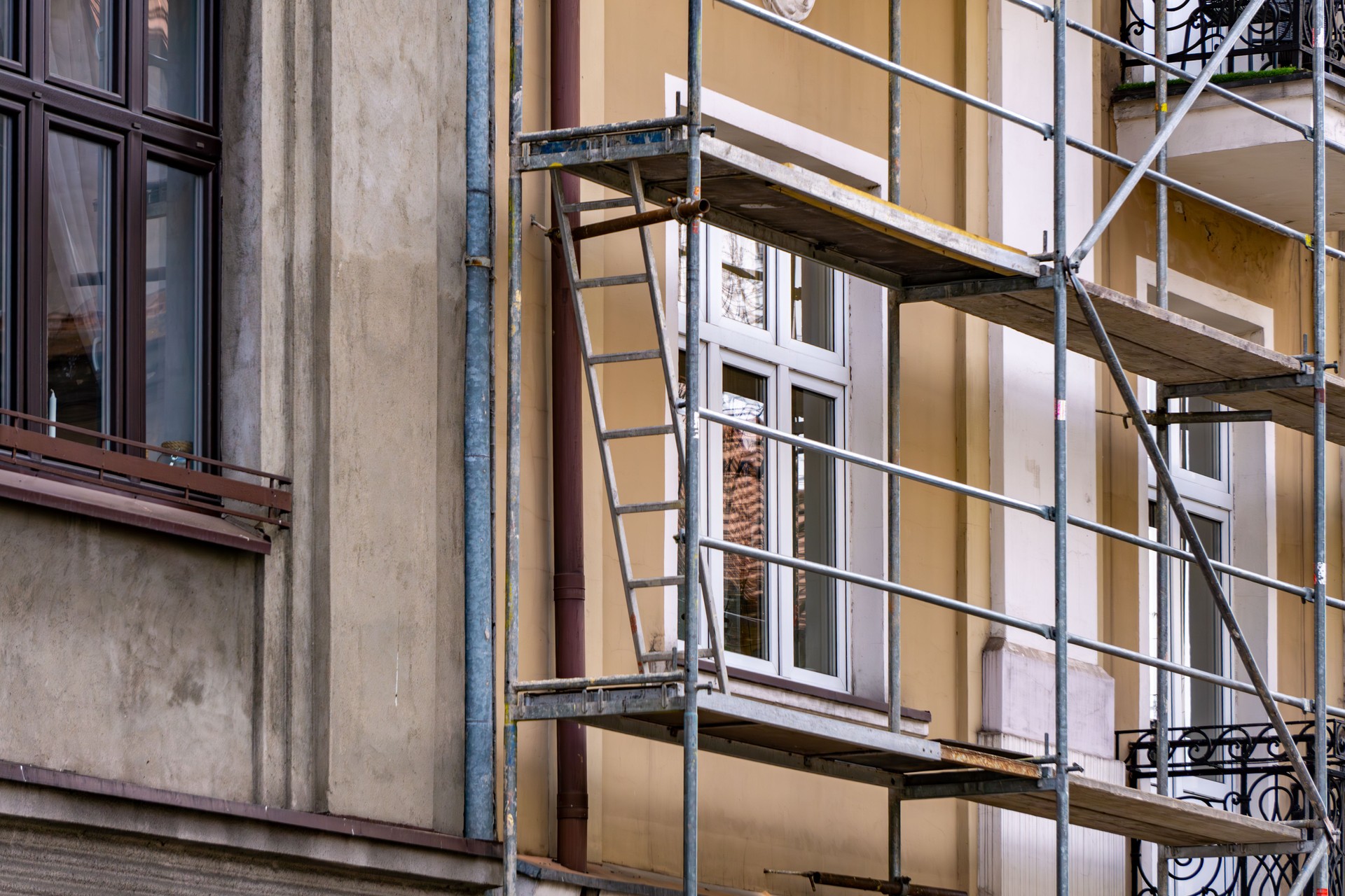 A fragment of the facade of a tenement house during renovation. The photo shows the scaffolding installed next to the building, as well as windows and architectural details of the facade.